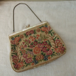 Puede incluir: Un bolso de mano vintage bordado con flores, con cierre de nácar y una cadena de oro.