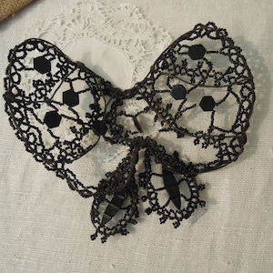May include: A black beaded butterfly ornament with a wire frame. The butterfly has a delicate, intricate design and is accented with black beads.
