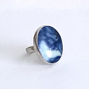 May include: A silver ring with a blue and white enamel inlay. The inlay has a swirling pattern.