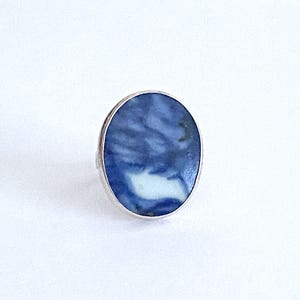 May include: A silver ring with a blue and white oval stone. The stone has a swirling pattern.