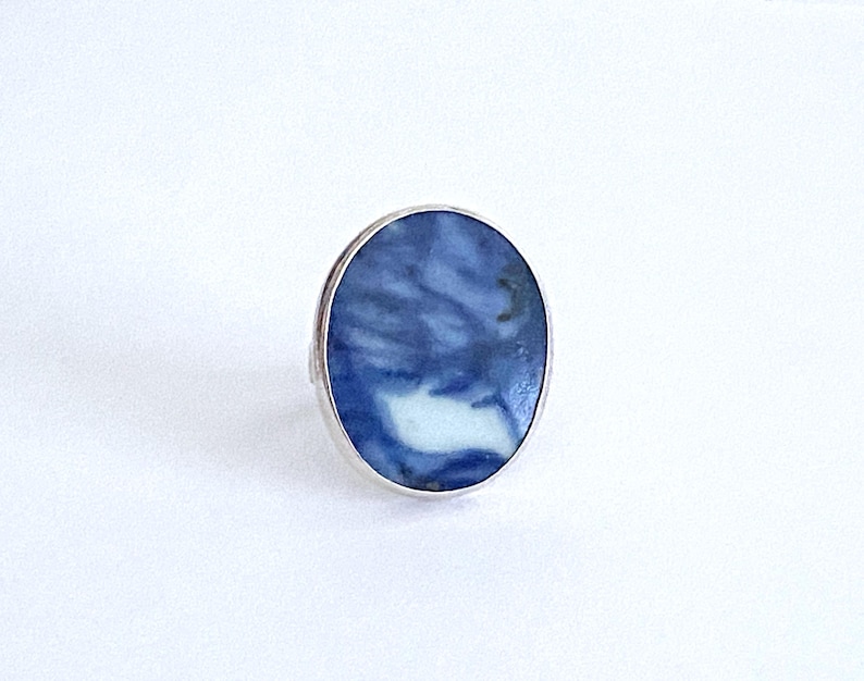 May include: A silver ring with a blue and white oval stone. The stone has a swirling pattern.