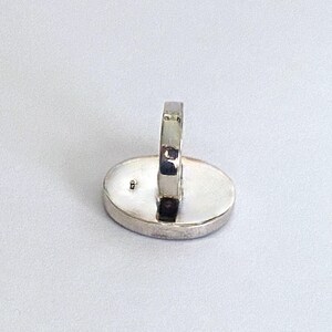 May include: A silver ring with a smooth oval-shaped setting. The ring is shown from the back, revealing the smooth band and the setting.