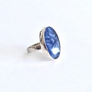 May include: A silver ring with a blue and white oval stone set in the center.