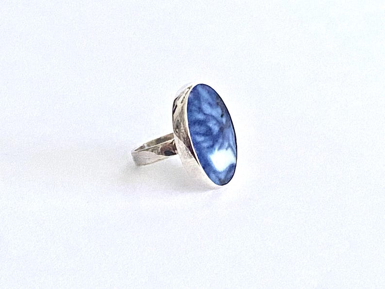 May include: A silver ring with a blue and white oval stone set in the center.