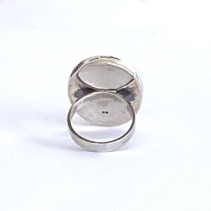 May include: Silver ring with a large oval-shaped stone. The ring is set in a hammered metal band.