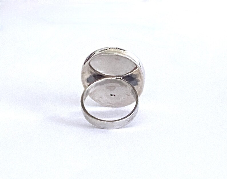 May include: Silver ring with a large oval-shaped stone. The ring is set in a hammered metal band.