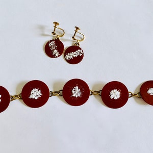 Peut inclure: Un ensemble de bijoux marrons et dor&eacute;s avec des paillettes blanches. L'ensemble comprend un bracelet &agrave; cinq maillons ronds et une paire de boucles d'oreilles avec un pendentif rond unique.