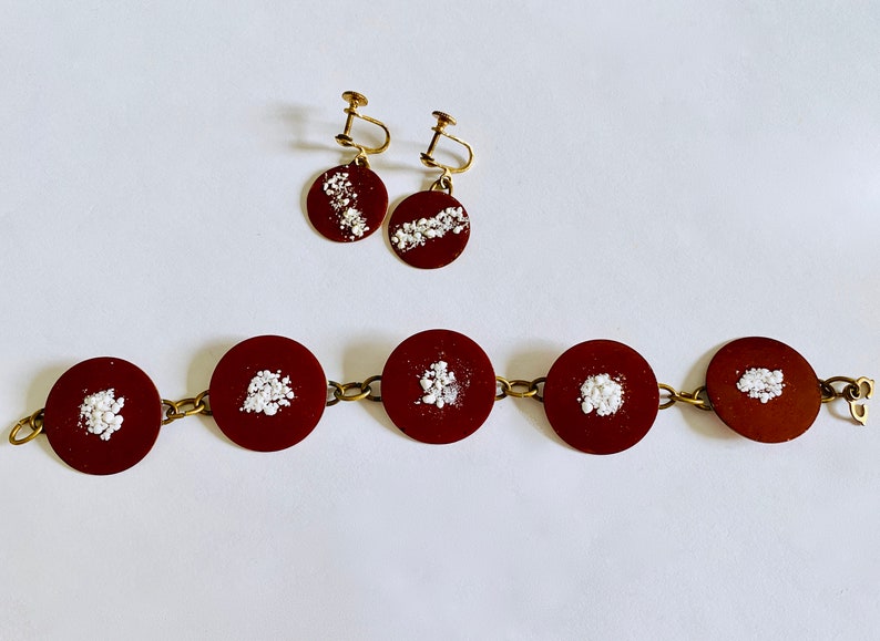 Peut inclure: Un ensemble de bijoux marrons et dor&eacute;s avec des paillettes blanches. L'ensemble comprend un bracelet &agrave; cinq maillons ronds et une paire de boucles d'oreilles avec un pendentif rond unique.
