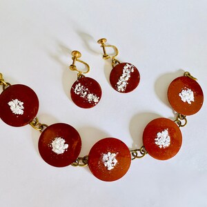 Peut inclure: Un bracelet marron et or avec cinq breloques rondes &agrave; motifs marrons et blancs. Deux boucles d'oreilles assorties avec le m&ecirc;me motif sont &eacute;galement incluses.
