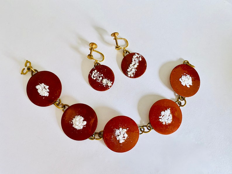 Peut inclure: Un bracelet marron et or avec cinq breloques rondes &agrave; motifs marrons et blancs. Deux boucles d'oreilles assorties avec le m&ecirc;me motif sont &eacute;galement incluses.