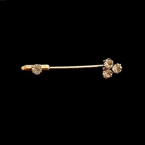 May include: A gold-toned safety pin with three clear rhinestones at the end.