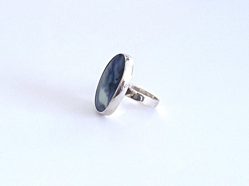 May include: A silver ring with a blue and white oval gemstone.