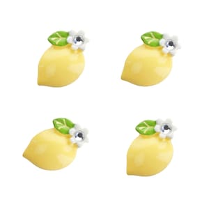 May include: Four yellow lemon-shaped ceramic embellishments with green leaves and white flowers with clear rhinestone centers.