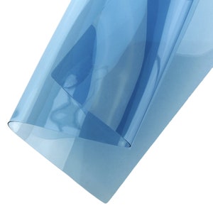 Può includere: Un rotolo di pellicola per la tinta delle finestre di colore blu chiaro. La pellicola è traslucida e ha una leggera lucentezza.