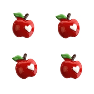 May include: Four red apple-shaped buttons with white heart designs. The buttons have green leaves and stems.