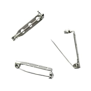 May include: Three silver-toned brooch backs, each with a pin and a safety catch. The backs are designed to be attached to the back of a brooch or pin.