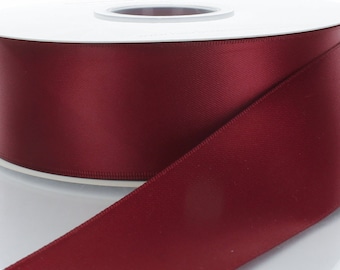 May include: A spool of deep red satin ribbon. The ribbon is smooth and shiny.