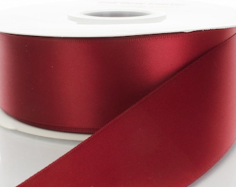 May include: A spool of deep red satin ribbon. The ribbon is wound around a white spool.