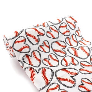 May include: White fabric with a repeating pattern of red and white baseballs in the shape of hearts. The fabric is rolled up.