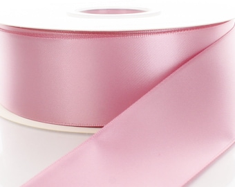 May include: A spool of pale pink satin ribbon. The ribbon is wound around a white spool.