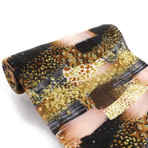 May include: Rolled fabric with a black, gold, and brown abstract print featuring animal print patterns.