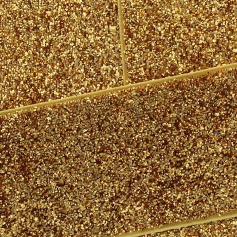 May include: Gold glitter fabric with a textured, sparkly surface. The fabric has a subtle diagonal pattern.