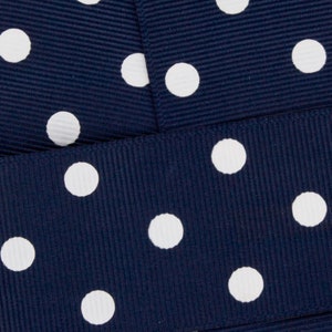 May include: Navy blue ribbon with white polka dots. The ribbon is folded in half, showing the pattern on both sides.