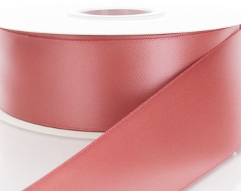May include: A spool of dusty rose satin ribbon. The ribbon is wound around a white spool and is shown unfurling.
