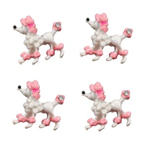 May include: Four miniature poodle figurines. Each poodle is white with pink accents on the ears, paws, and tail. The poodles have a rhinestone on their rear. The poodles are in a walking pose.