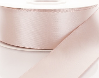 May include: A spool of pale pink satin ribbon. The ribbon is wound around a white spool and is ready to be used for crafting, gift wrapping, or decorating.