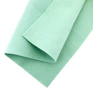 May include: A folded piece of light green felt fabric. The fabric is soft and has a smooth texture.