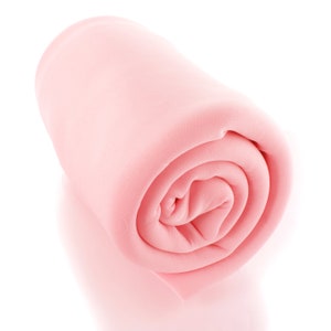 Puede incluir: Un rollo de tela rosa claro, bien enrollado. El material parece ligero, posiblemente un tejido de punto o tejido, con una textura suave. El rollo está sobre un fondo blanco, resaltando su color y forma.