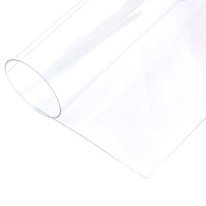 May include: A clear plastic sheet rolled up, showing the smooth, transparent surface. The sheet is flexible and can be used for various craft projects.