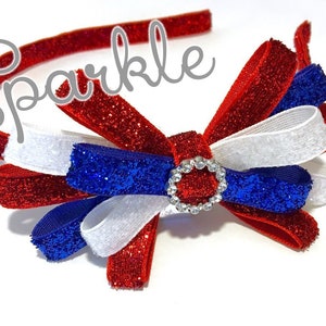 May include: Red, white, and blue glitter headband with a bow and a rhinestone center. The headband says "Sparkle" on it.