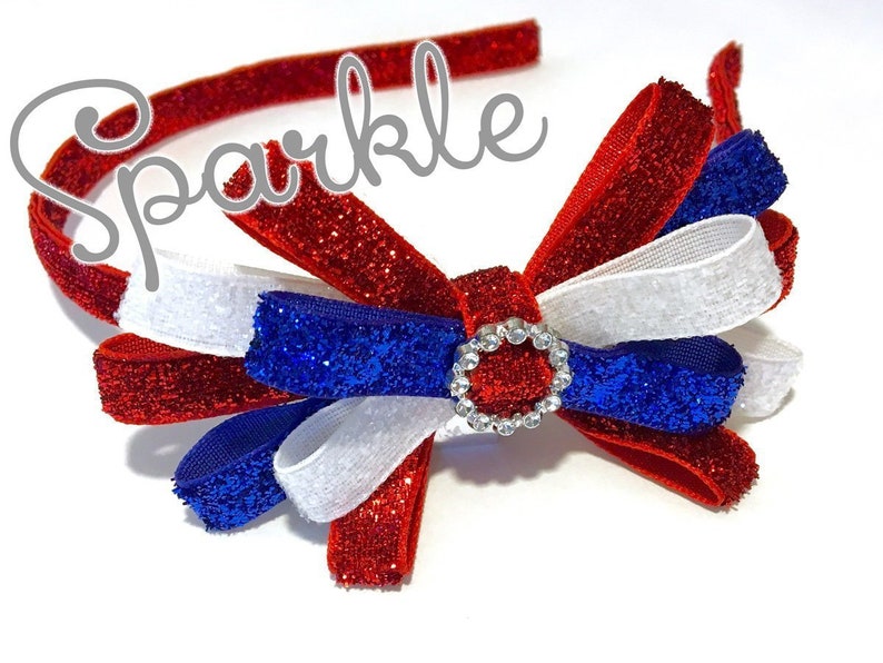 May include: Red, white, and blue glitter headband with a bow and a rhinestone center. The headband says "Sparkle" on it.
