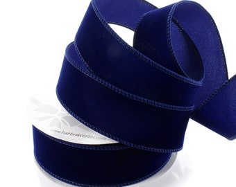 May include: A roll of navy blue velvet ribbon with stitched edges. The ribbon is thick and plush, with a soft sheen. The white label at the base of the roll has the website address www.hairbowcenter.com.