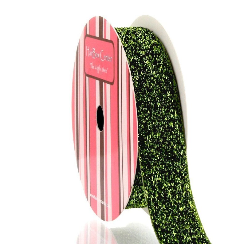 May include: A spool of green glitter ribbon with a pink and white striped label that reads "HairBow Center The supply store".