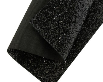 May include: Black glitter fabric with a smooth, even texture. The fabric is folded in half, showing the back side, which is a solid black.