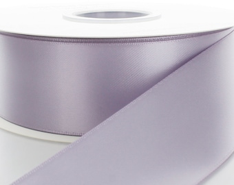 May include: A spool of lavender satin ribbon. The ribbon is wound around a white cardboard spool.