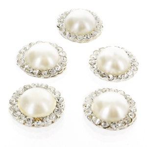 May include: Five white pearl embellishments with a clear rhinestone border. Each pearl is surrounded by a circle of rhinestones.