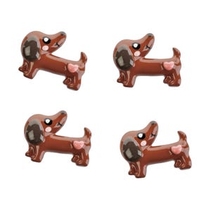 May include: Four brown dachshund figurines with pink hearts on their tails. The dachshunds have black noses and brown eyes.