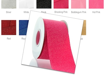 May include: A spool of pink glitter ribbon. The ribbon is on a white spool and is wrapped around a white cardboard core.