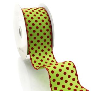 May include: A spool of wired ribbon with a bright green background and red polka dots. The ribbon has a red stitched edge and is partially unrolled, showing the pattern. The spool is white.