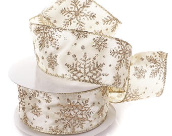 May include: Ivory-colored ribbon with gold glitter snowflake designs. The ribbon is rolled on a white cardboard spool. The snowflakes are of varying sizes and are evenly spaced across the ribbon's surface. The edges of the ribbon are trimmed with gold.