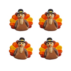 Könnte beinhalten: Vier Keramik-Thanksgiving-Truthahn-Figuren mit braunen Körpern, orangefarbenen und gelben Federn und schwarzen Pilgerhüten.