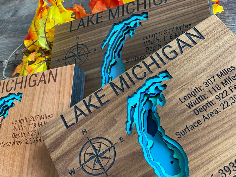 Puede incluir: Un letrero de madera con un mapa en relieve azul y verde del lago Michigan. El letrero incluye el texto "LAKE MICHIGAN" y las dimensiones del lago: Longitud: 307 millas, Ancho: 118 millas, Profundidad: 922 pies, &Aacute;rea de superficie: 22.394 millas cuadradas.