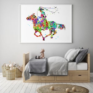May include: A framed watercolour print depicting a cowboy on horseback, created in a vibrant splatter-paint style. The artwork shows a cowboy with a lasso, riding a horse with colourful splashes of red, blue, green, and yellow. The print is displayed above a child's bed.