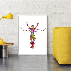 May include: A colorful watercolor painting of a cyclist crossing a finish line with arms raised in victory. The cyclist is depicted in a vibrant array of colors, with a splash of yellow, red, blue, green, and purple.
