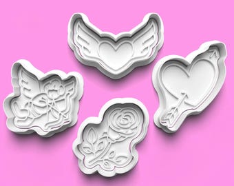 May include: Set of four white plastic cookie cutters shaped like a heart with wings, a heart with an arrow, a rose, and an angel with an arrow.