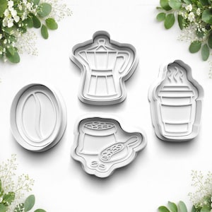 Pode incluir: Quatro cortadores de biscoitos de plástico branco em formas de café: um grão de café, uma cafeteira italiana, um saco de grãos de café com uma colher e uma xícara de café para viagem com vapor. Em uma superfície branca com vegetação.